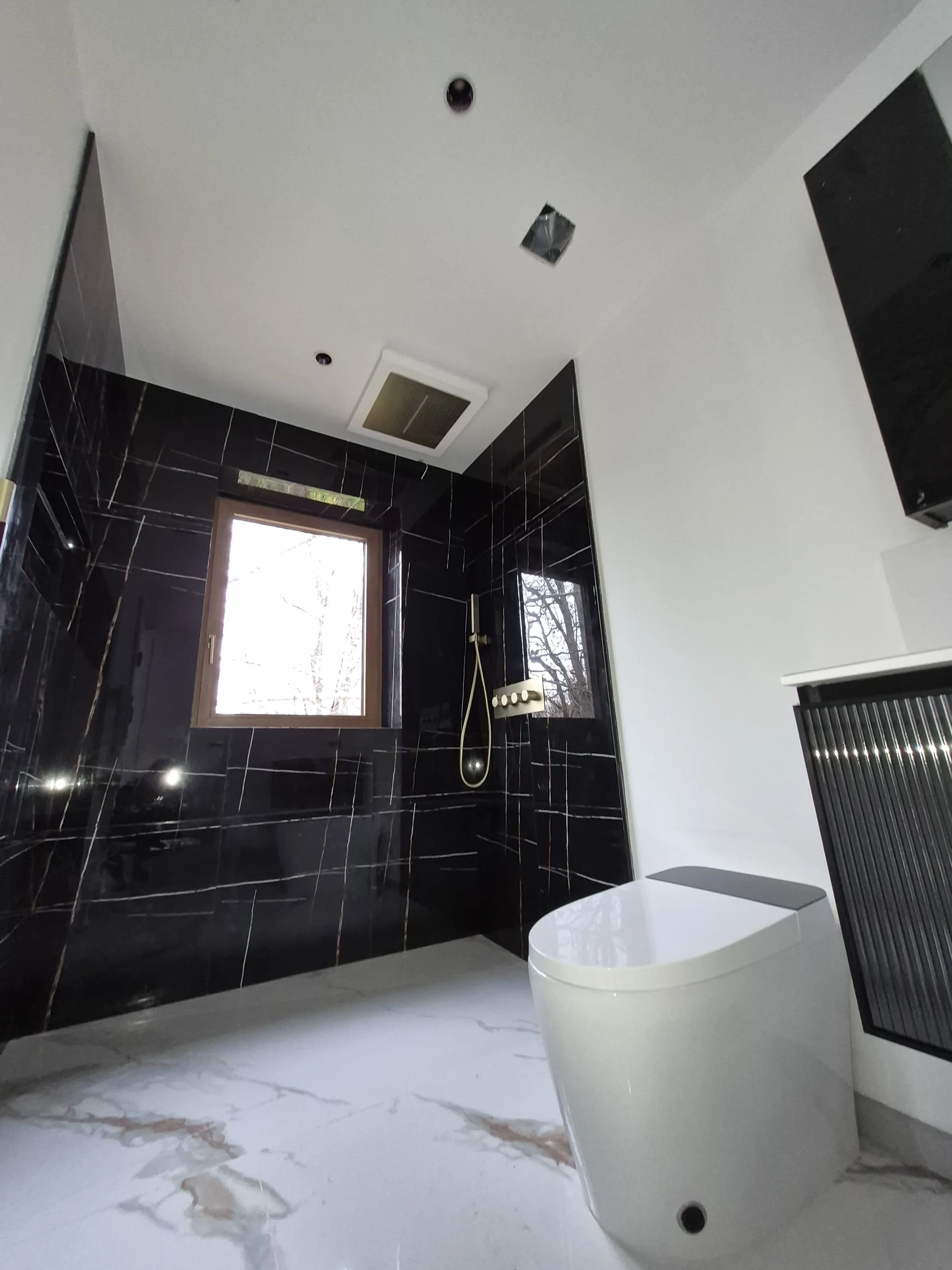 Brass plumbing-fixture detail — wall-mounted basin spout against marble vanity wall