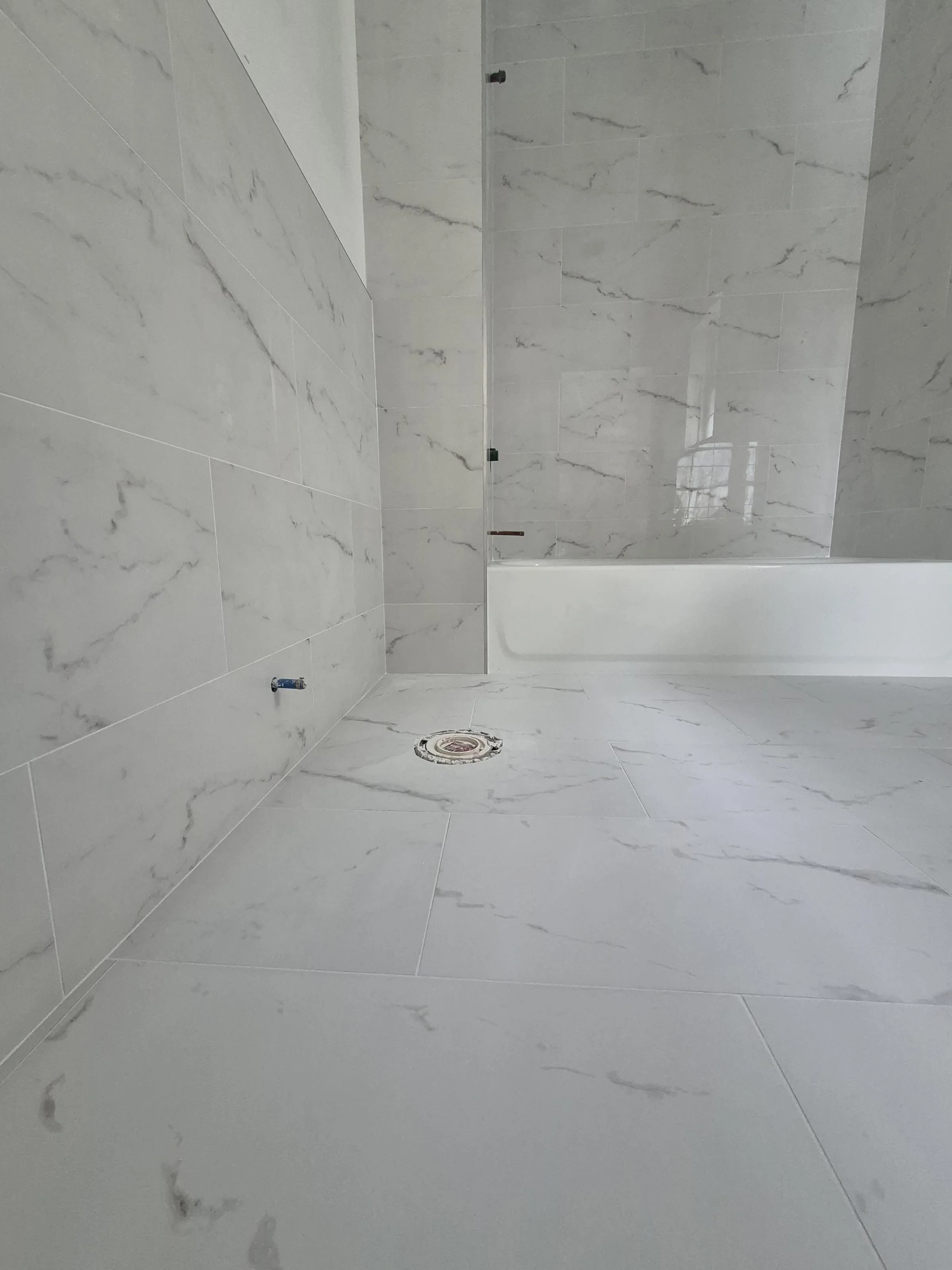 Marble walk-in shower with freestanding tub — bookmatched marble panels, brass body sprays, hex marble floor