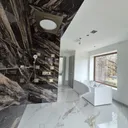 Luxury master bathroom — bookmatched marble shower wall, brass fixtures, freestanding smart-control tub