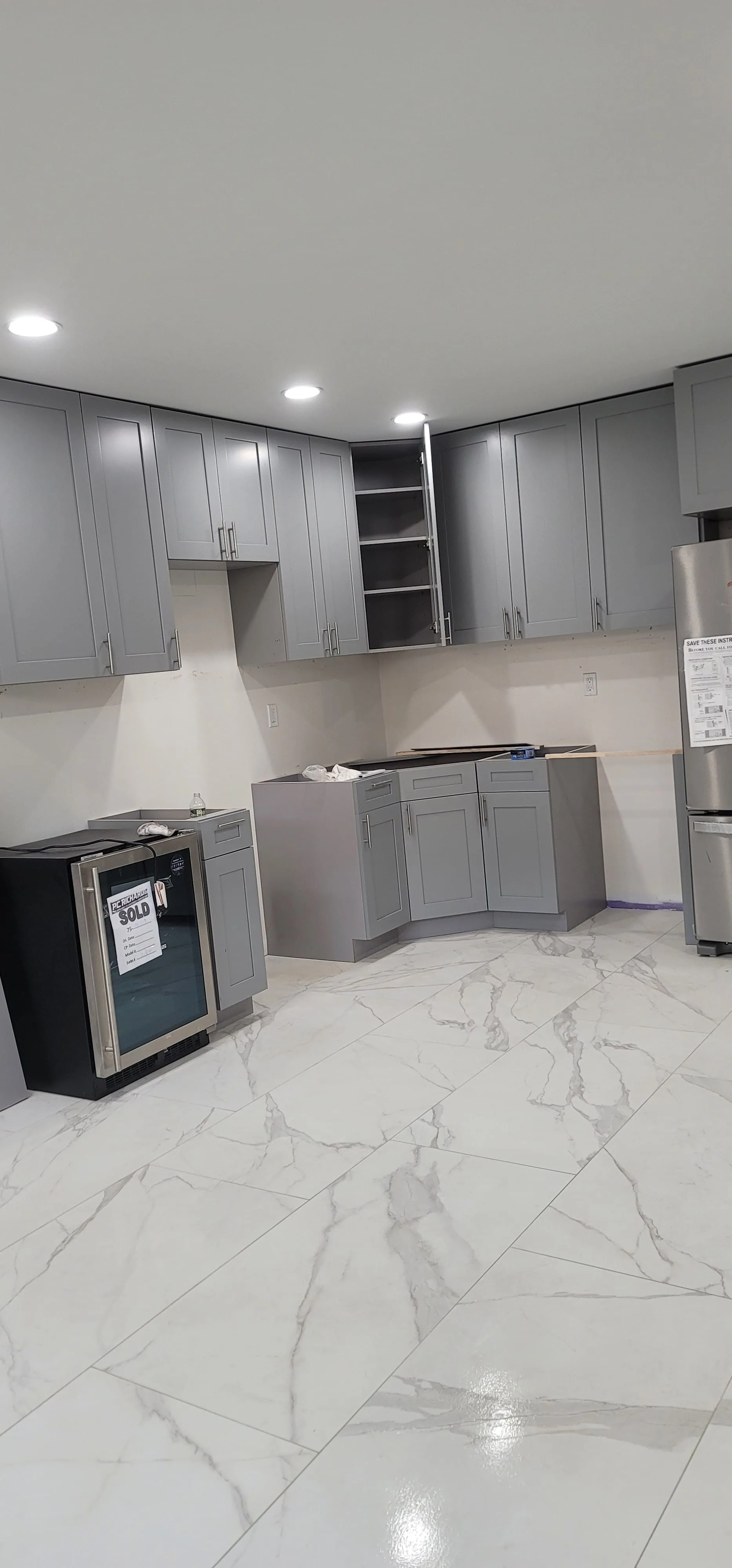 High-end modern kitchen remodel with custom cabinetry, marble waterfall island, and integrated flooring run