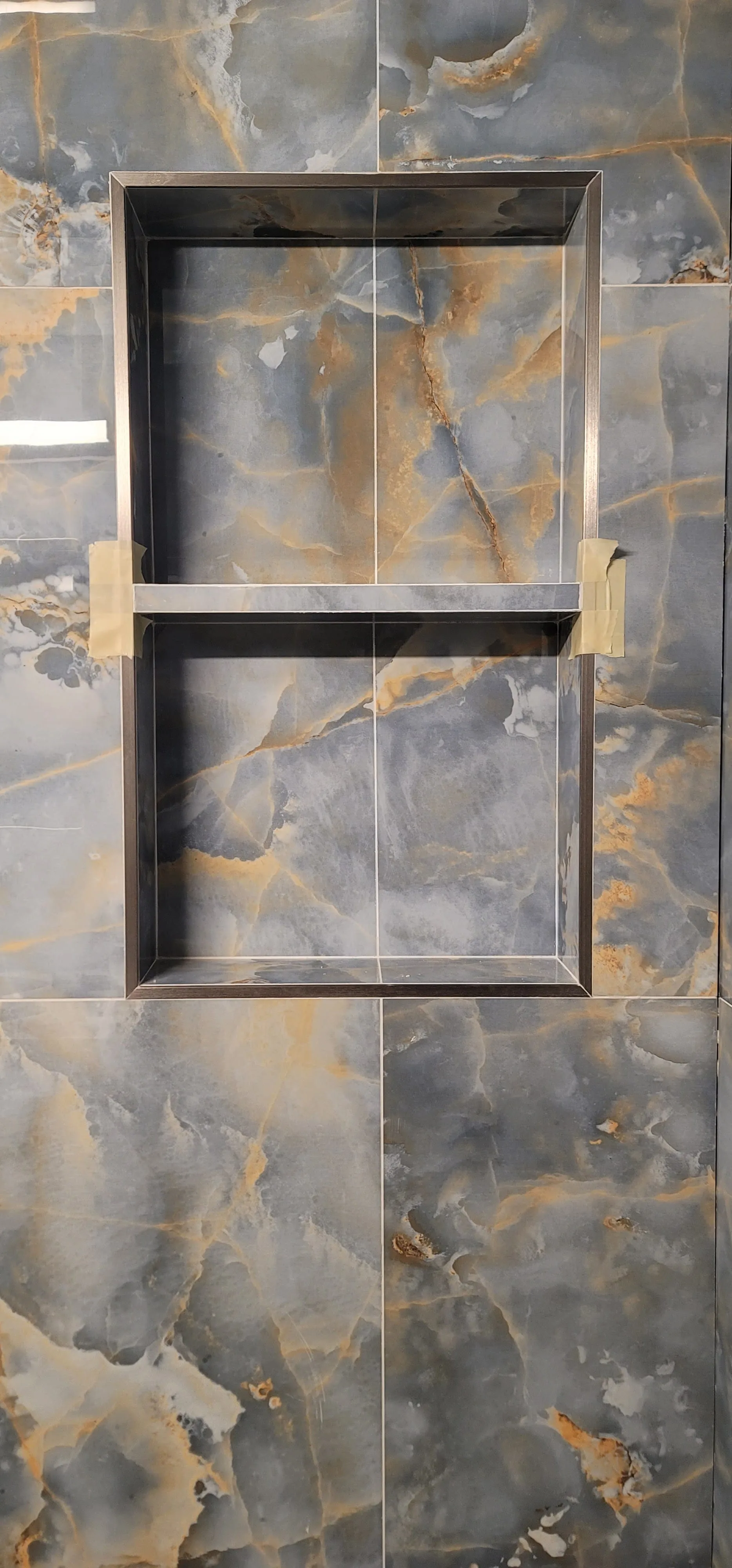 Powder-room mosaic feature wall — blue and gold onyx with steel-rimmed double niche, hand-set chip layout